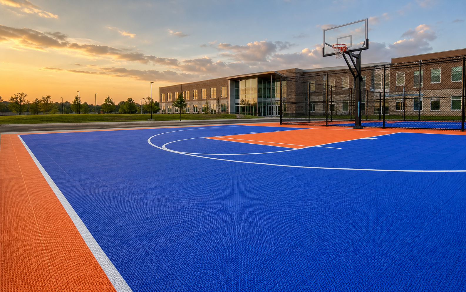 Blue and orange modular basketball court outside a school at sunset